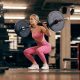 A-happy-strong-sporty-woman-is-doing-squats-while-lifting-barbell-in-a-gym