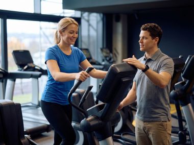 Happy-sportswoman-working-out-on-cross-trainer-during-exercise-class