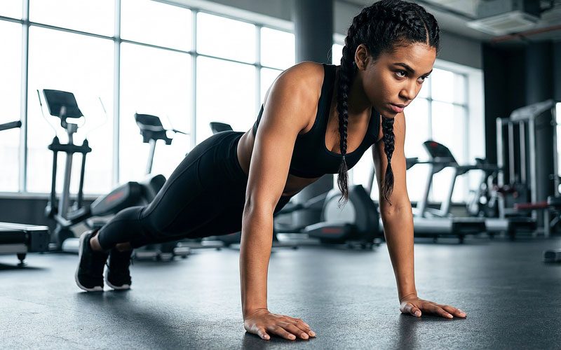 Sporty-woman-performing-push-ups-from-the-floor-in-the-gym